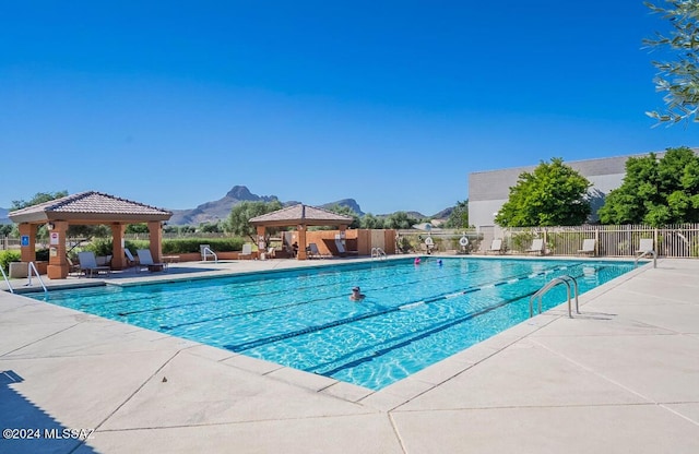 community pool with fence, a gazebo, a patio, and a mountain view