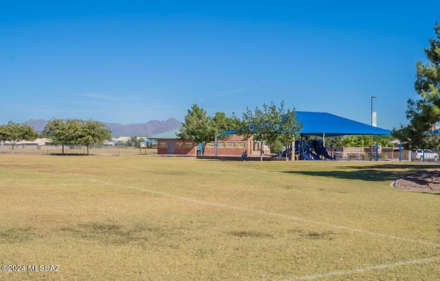 surrounding community featuring fence, playground community, and a mountain view
