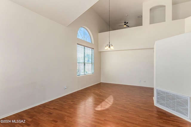 empty room with visible vents, wood finished floors, a wealth of natural light, and high vaulted ceiling