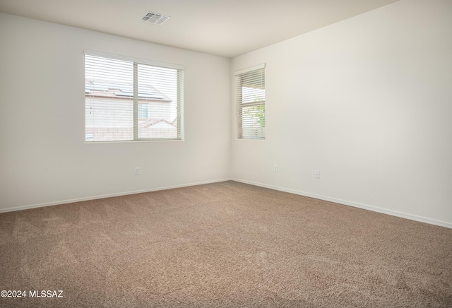 carpeted empty room featuring visible vents and baseboards