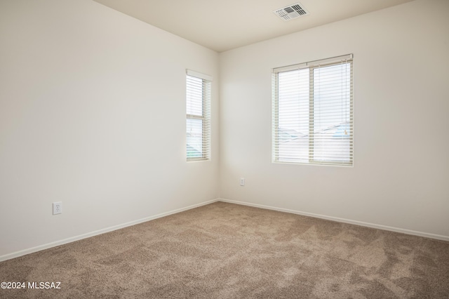 empty room featuring carpet floors, visible vents, and baseboards