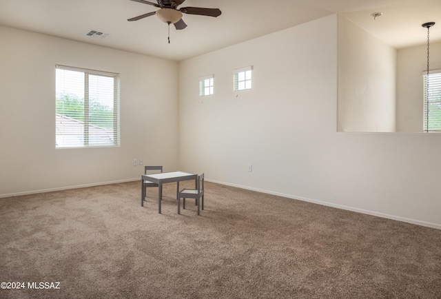 carpeted spare room with baseboards, visible vents, and ceiling fan