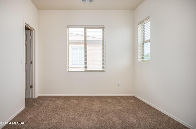 unfurnished room featuring carpet flooring, visible vents, and baseboards