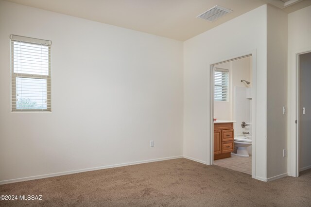 unfurnished bedroom with light carpet, ensuite bath, visible vents, and baseboards