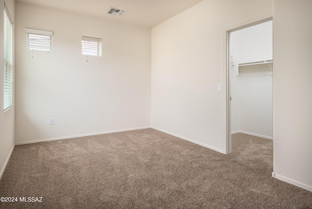 unfurnished bedroom featuring carpet floors, visible vents, baseboards, a spacious closet, and a closet