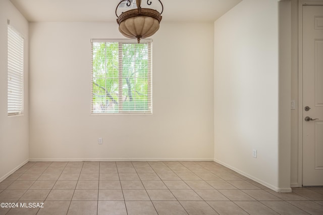 empty room with baseboards and light tile patterned floors