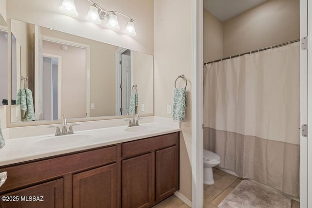 bathroom featuring double vanity, a sink, tile patterned floors, and toilet