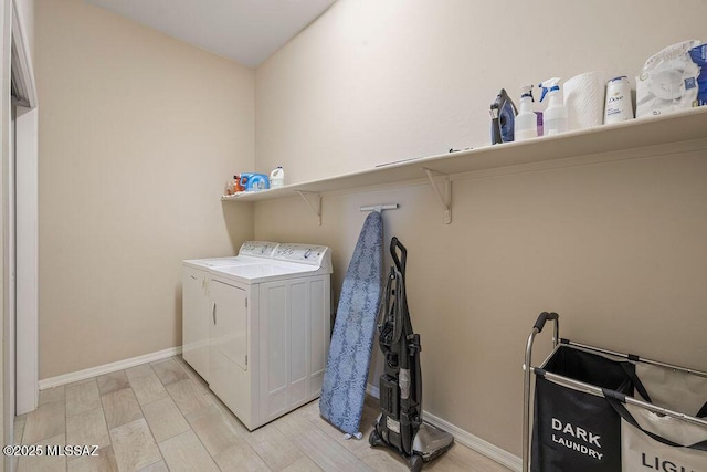 laundry area with baseboards, separate washer and dryer, laundry area, and light wood-style flooring