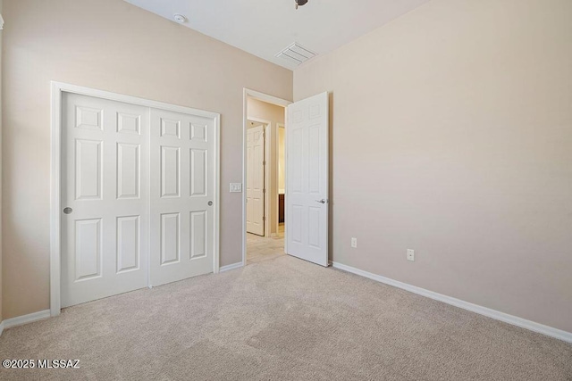 unfurnished bedroom featuring light colored carpet, baseboards, visible vents, and a closet