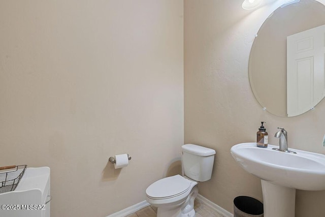bathroom featuring toilet, baseboards, and a sink