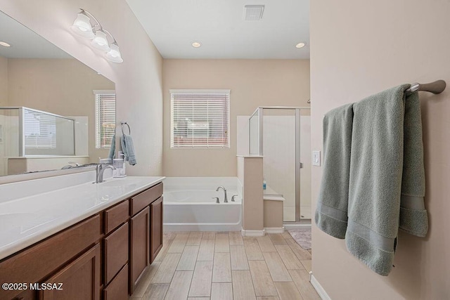 full bath with a bath, visible vents, a stall shower, wood finished floors, and vanity