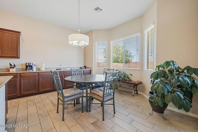 dining space with visible vents, light wood-style flooring, baseboards, and a chandelier