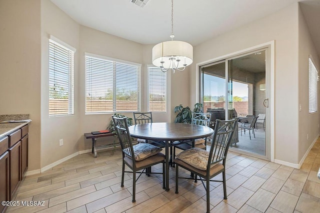 dining area with baseboards, light wood-type flooring, a chandelier, and visible vents
