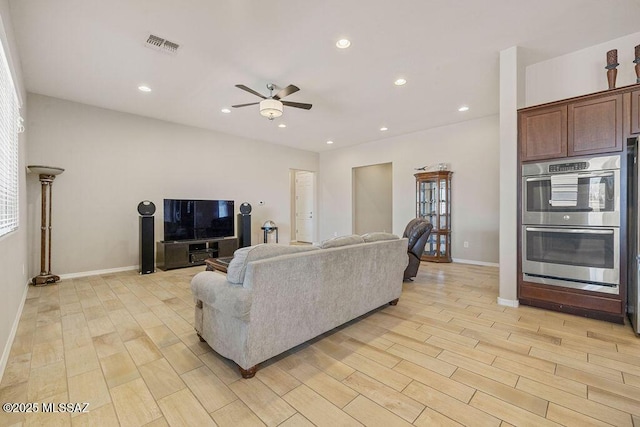 living room with ceiling fan, visible vents, baseboards, and light wood-style floors