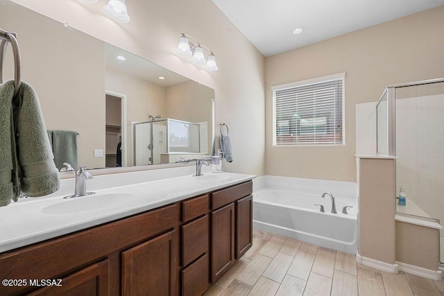 bathroom featuring a sink, double vanity, a shower stall, and a bath