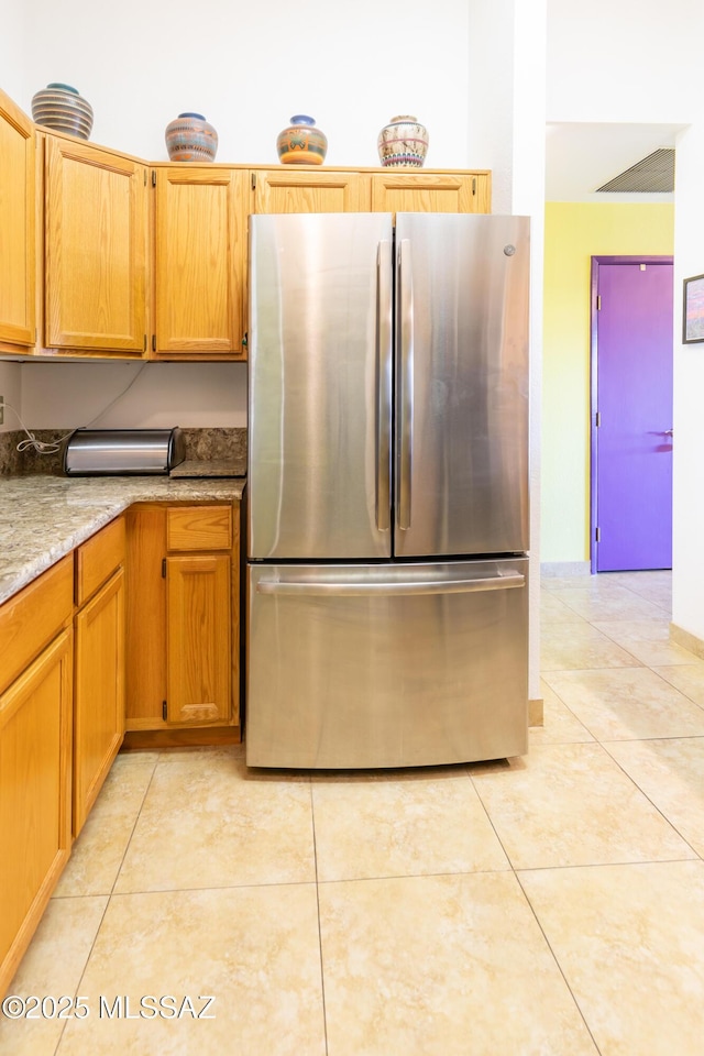 kitchen featuring light tile patterned floors and stainless steel fridge