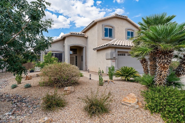 mediterranean / spanish-style house with stucco siding, an attached garage, and a tiled roof