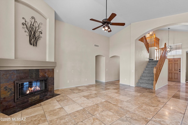 9797 E Holden Pl, Tucson, AZ 85748 - unfurnished living room featuring ceiling fan, a towering ceiling, stairway, a fireplace, and arched walkways