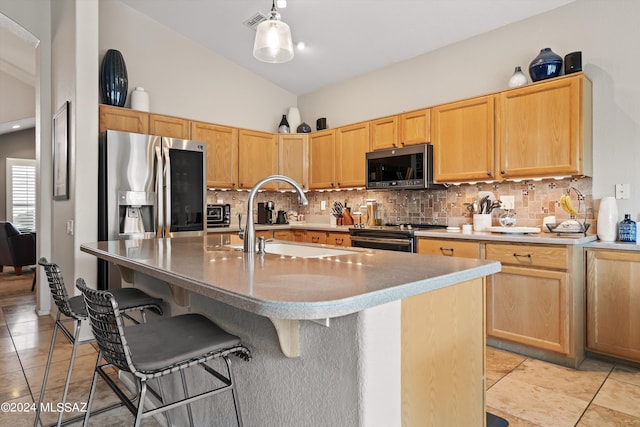 kitchen with lofted ceiling, tasteful backsplash, a center island with sink, sink, and stainless steel appliances