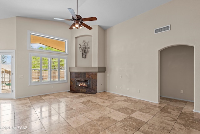 9797 E Holden Pl, Tucson, AZ 85748 - unfurnished living room featuring a high ceiling, ceiling fan, arched walkways, and a tiled fireplace