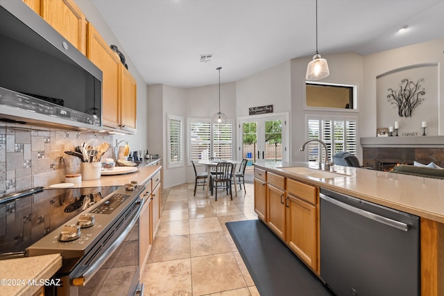 kitchen featuring appliances with stainless steel finishes, decorative light fixtures, tasteful backsplash, sink, and light tile patterned floors