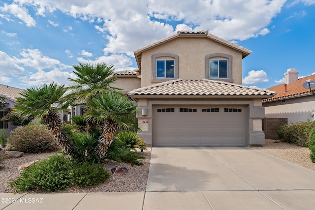 mediterranean / spanish house featuring a tile roof, stucco siding, a garage, and concrete driveway