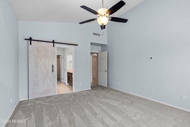 9797 E Holden Pl, Tucson, AZ 85748 - unfurnished bedroom featuring light carpet, a barn door, high vaulted ceiling, ensuite bath, and a ceiling fan