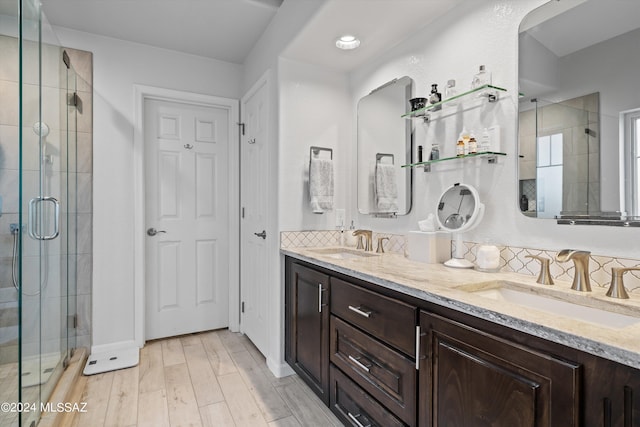 bathroom with vanity, wood-type flooring, tasteful backsplash, and an enclosed shower