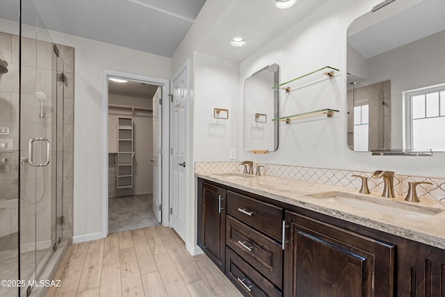 9797 E Holden Pl, Tucson, AZ 85748 - full bath featuring a stall shower, wood finished floors, double vanity, backsplash, and a spacious closet
