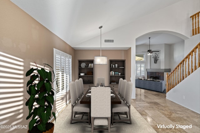 9797 E Holden Pl, Tucson, AZ 85748 - dining area featuring a ceiling fan, a fireplace, arched walkways, built in shelves, and high vaulted ceiling