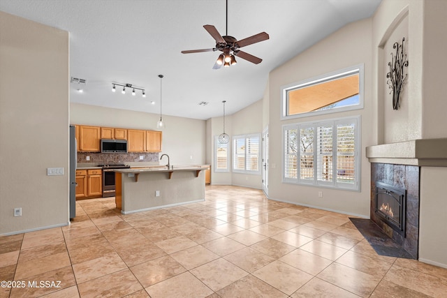 9797 E Holden Pl, Tucson, AZ 85748 - kitchen featuring stainless steel appliances, light countertops, tasteful backsplash, a tiled fireplace, and a ceiling fan