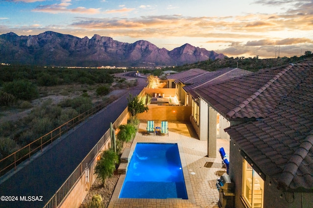 pool at dusk featuring a mountain view and a patio area