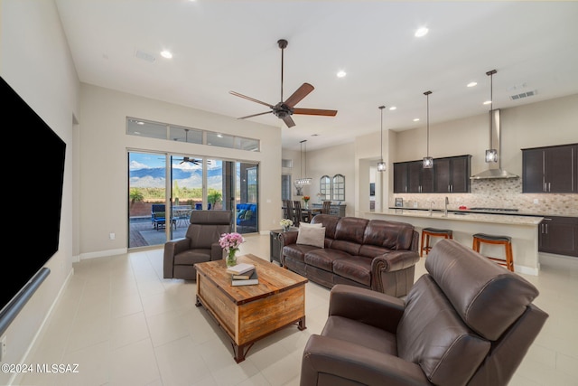 tiled living room featuring ceiling fan and sink