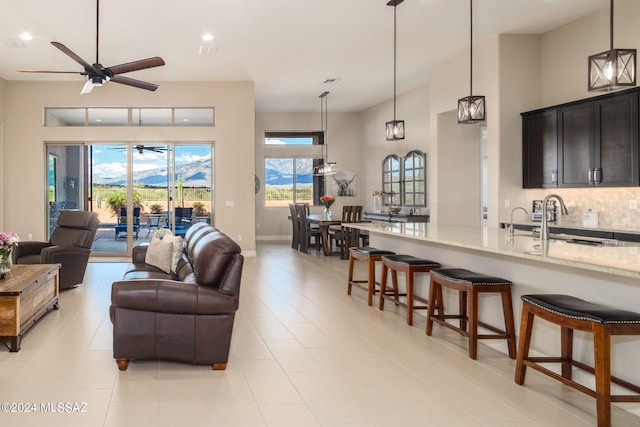 living room with ceiling fan, light tile patterned flooring, sink, and a high ceiling