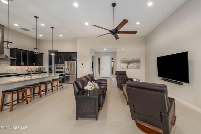 living room featuring light tile patterned floors, sink, and ceiling fan