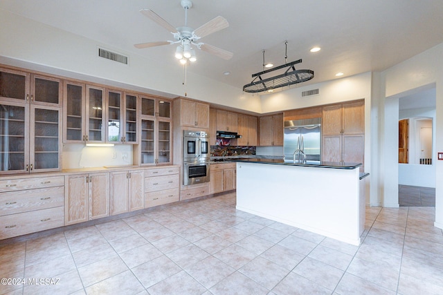 kitchen featuring ceiling fan, light tile patterned flooring, appliances with stainless steel finishes, and an island with sink