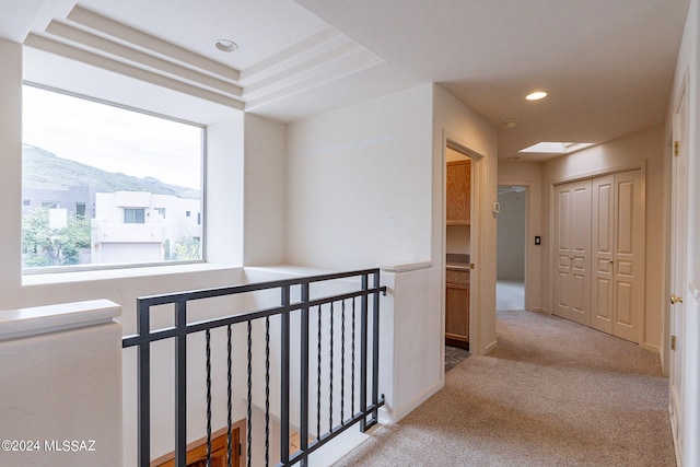 corridor with light colored carpet, a tray ceiling, and a mountain view