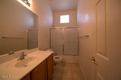 full bathroom featuring vanity, toilet, bath / shower combo with glass door, and tile patterned floors