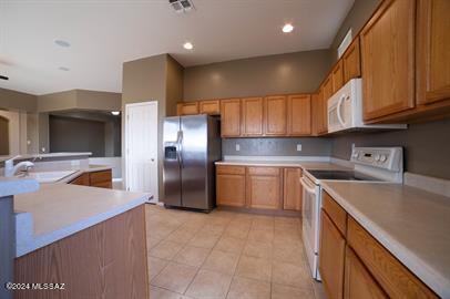 kitchen featuring sink, light tile patterned floors, and white appliances