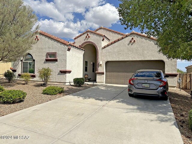 mediterranean / spanish house featuring concrete driveway, a tile roof, an attached garage, and stucco siding