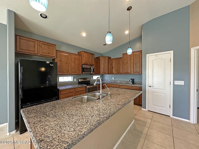 kitchen featuring brown cabinets, light tile patterned floors, appliances with stainless steel finishes, a sink, and an island with sink