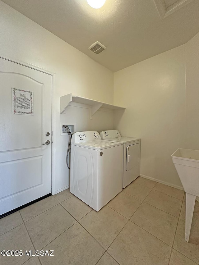 clothes washing area featuring laundry area, light tile patterned floors, baseboards, visible vents, and washer and clothes dryer