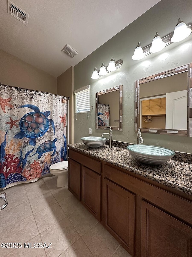 full bath with toilet, visible vents, and a sink