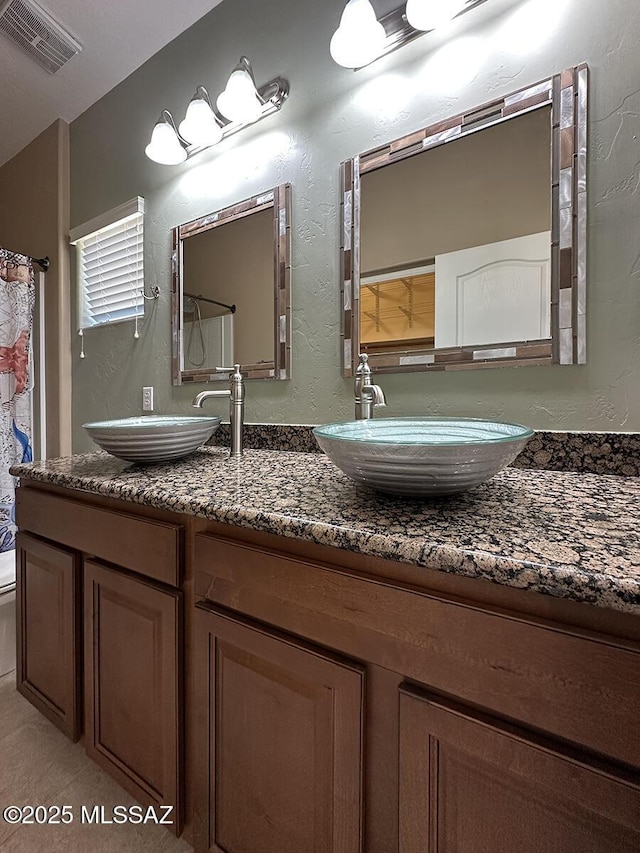 full bathroom featuring a textured wall, visible vents, a sink, and toilet