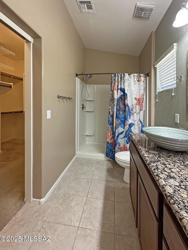 bathroom with toilet, a stall shower, a walk in closet, and visible vents