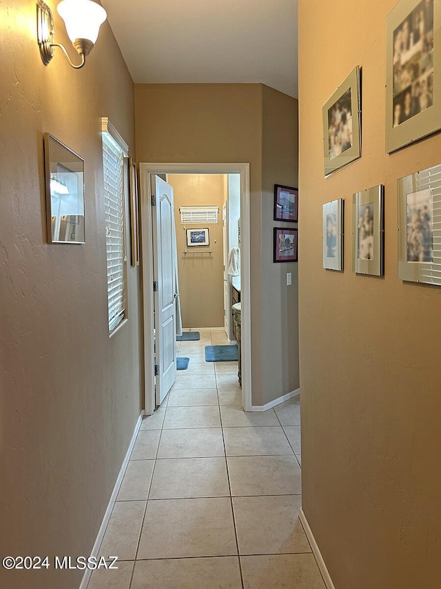 hall with light tile patterned flooring and baseboards