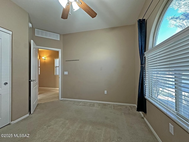 unfurnished bedroom featuring light carpet, multiple windows, visible vents, and baseboards