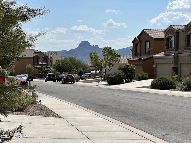 view of street with curbs, a residential view, sidewalks, and a mountain view