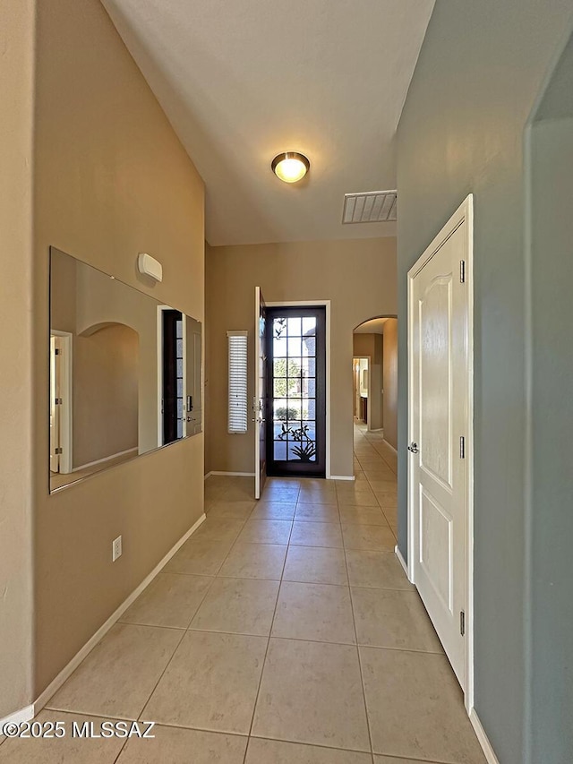 foyer entrance featuring arched walkways, visible vents, baseboards, and light tile patterned floors