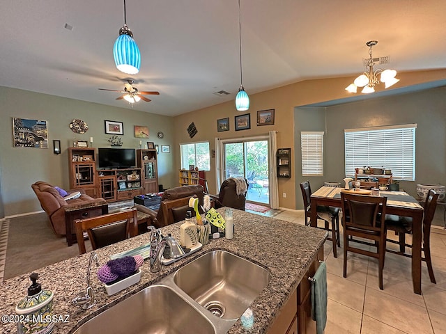 kitchen with ceiling fan with notable chandelier, sink, light tile patterned floors, decorative light fixtures, and dark stone countertops